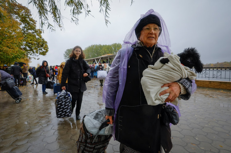 Civilians evacuated from the Russian-controlled city of Kherson walk from a ferry to board a bus heading to Crimea in the town of Oleshky on October 23..