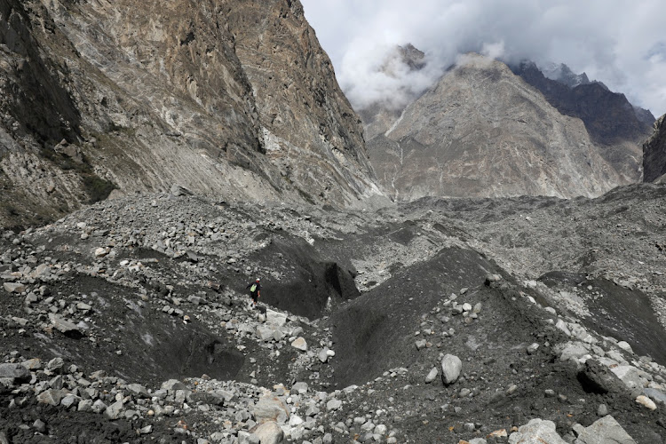 Tariq Jamil, 51, chair of the Community Based Disaster Risk Management Centre, walks with a hiking stick to check the ice on the Shisper glacier, near Hassanabad village, Hunza valley, in the Karakoram mountain range in the Gilgit-Baltistan region of Pakistan, on October 10 2023.