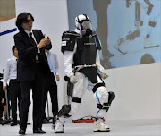 University of Tsukuba professor and president of Cyberdyne Yoshiyuki Sankai (L) unveils a robot suit entitled HAL (Hybrid Assistive Limb) at the Japan Robot Week exhibition in Tokyo. The new type of robot suits are to be used by workers at nuclear disaster sites and will be field tested at TEPCO's Fukushima power plant.