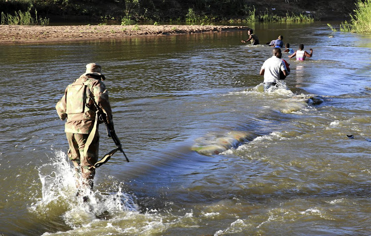 An SA soldier chases people who crossed into SA from Zimbabwe illegally to buy food in the border town of Musina.