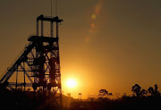 A derelict gold mine shaft's winding gear sits in front of the setting sun on July 15, 2013 in Johannesburg, South Africa.