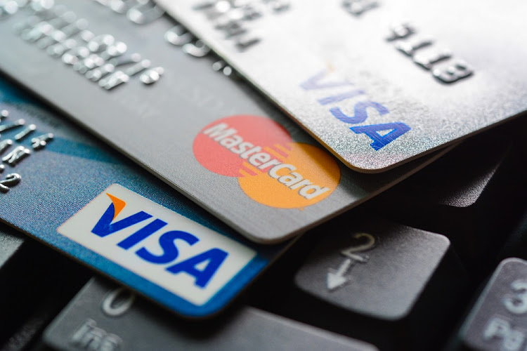 Group of credit cards on computer keyboard with VISA and MasterCard brand logos.