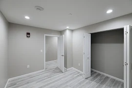 Bedroom with wood-inspired flooring, double white sliding door closet, light walls, white trim and view of entryway door