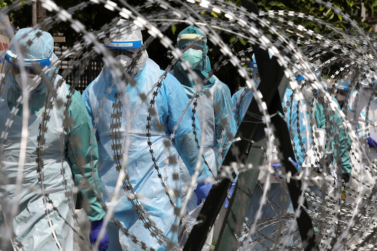 Medical workers wearing protective suits pass by barbed wire at the red zone under enhanced lockdown, amid the coronavirus disease (COVID-19) outbreak, in Petaling Jaya, Malaysia May 11 2020.