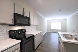 Kitchen with gray cabinets, black appliances, and tile backsplash