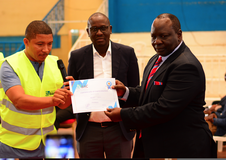 New KPBC chairman Rueben Ndolo receives his certificate from the elections returning officer Brian Weke (L) as outgoing boss Hillary Alila (C) looks on