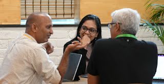 A man is talking to a woman and a man all sitting on a chair.