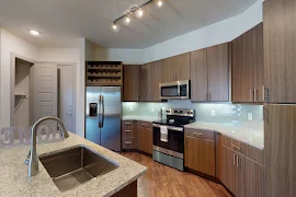 Kitchen with sink in island, wood inspired flooring, upper and lower cabinets, stainless steel appliances, and wine rack