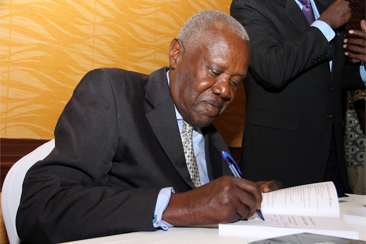 Lt Gen (Rtd) Daniel Opande autographs a copy of the book