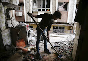 A young man cleans a damaged house in the besieged town of Douma, Eastern Ghouta, Damascus, Syria February 25, 2018. 