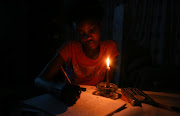 A student studying by candlelight during load-shedding. File photo. 