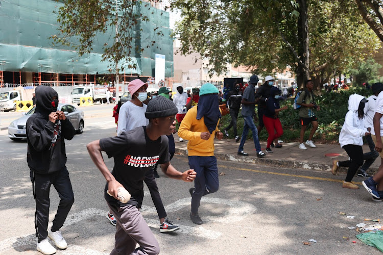 Protesting students run from one entrance to another outside the University of the Witwatersrand in Johannesburg on March 3 2023.