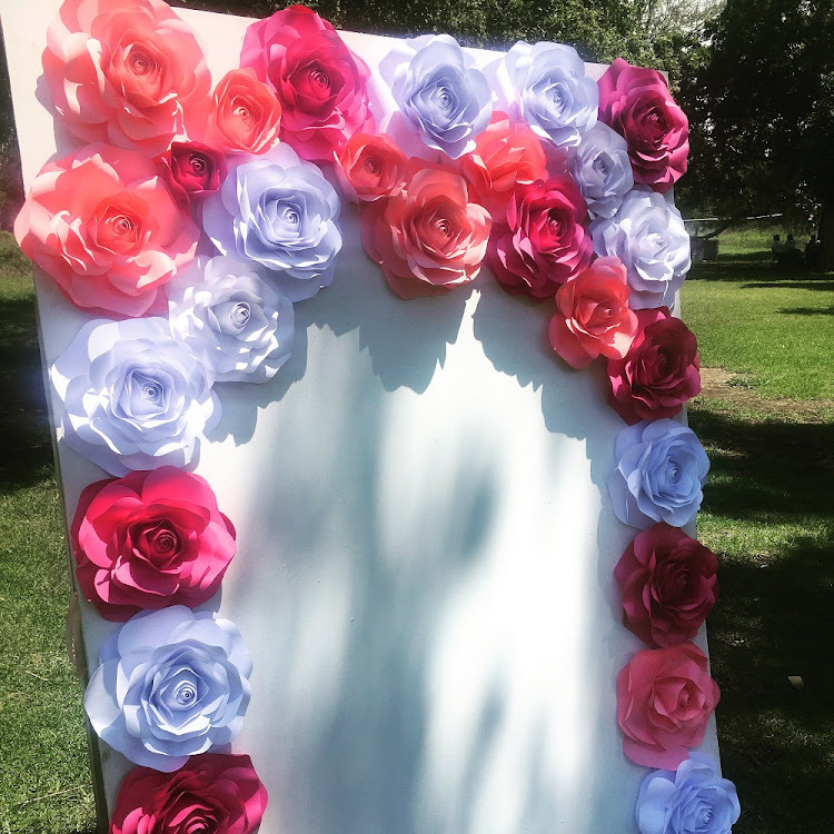 A photo frame wall decorated with Pearl's paper roses.