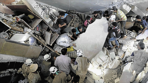 SEARCH ON: Civil defence members and civilians search for survivors under the rubble of a site hit by what activists said were cluster bombs dropped by the Russian air force in the town of Maasran, south of Idlib, in Syria yesterday. Picture: REUTERS