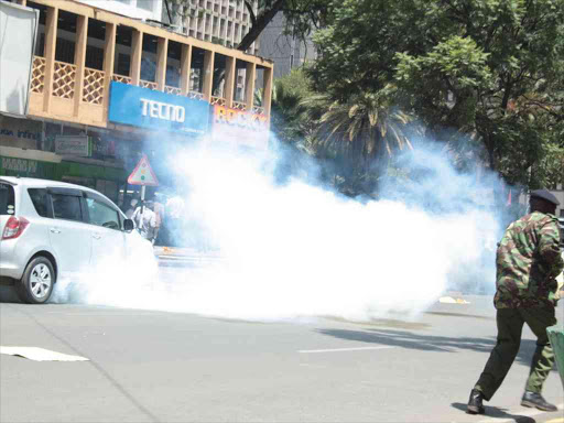 A police officer fires tear gas at civil society members who protested against the TV stations shutdown along Harambee Avenue in Nairobi, February 5, 2018. /Joseph Ndunda