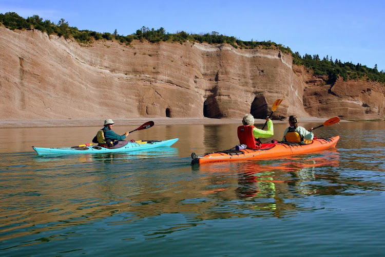 Kayakers explore the St. Martins Sea Caves, 25 miles east of St. John on the Bay of Fundy in Atlantic Canada. 