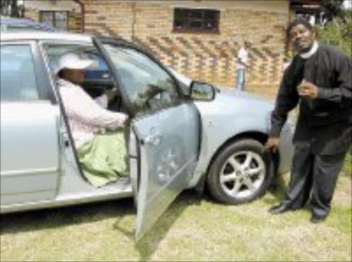 PROTECTION: Reverend Mlawuli Mayekiso blessing the car of Sheila Meko during a special ceremony, a first of its kind, of blessing cars at the African Methodist Episcopal Church in White City Jabavu in Soweto on Saturday. Pic. Munyadziwa Nemutudi. 03/02/08. © Sowetan.