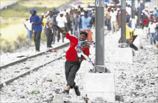 FRUSTRATION: Miners and residents throw rocks at police near Implats' Rustenburg mine last week as a month-long strike turned violent. PHOTO: REUTERS