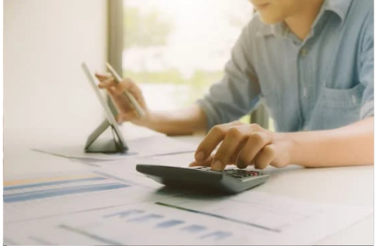 a person calculating lost earning capacity on a calculator while working on a tablet