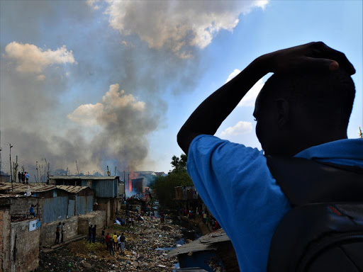 A man watches in disbelief as the fire destroys houses in Mukuru slums, March 2, 2019. /FAITH MUTEGI