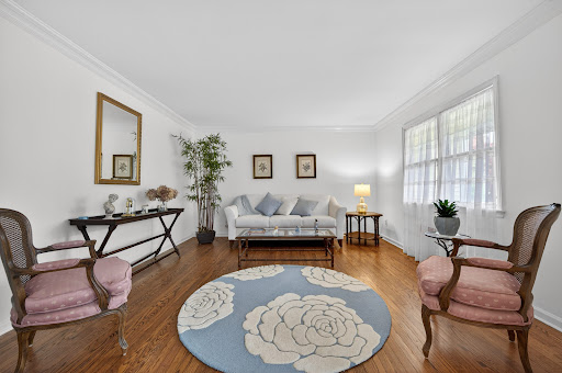 Living room with pink armchairs and round rug in this luxury property for sale in Locust Valley ($1,259,000)