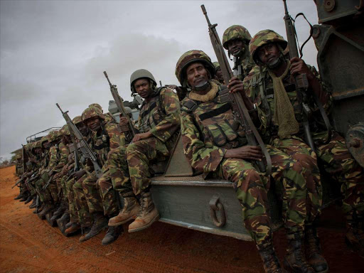 Soldiers of the Kenyan Contingent serving with the African Union Mission in Somalia sit on a flat-bed truck as a convoy makes its way between the port of Kismayo and the city's airport on October 2, 2012.