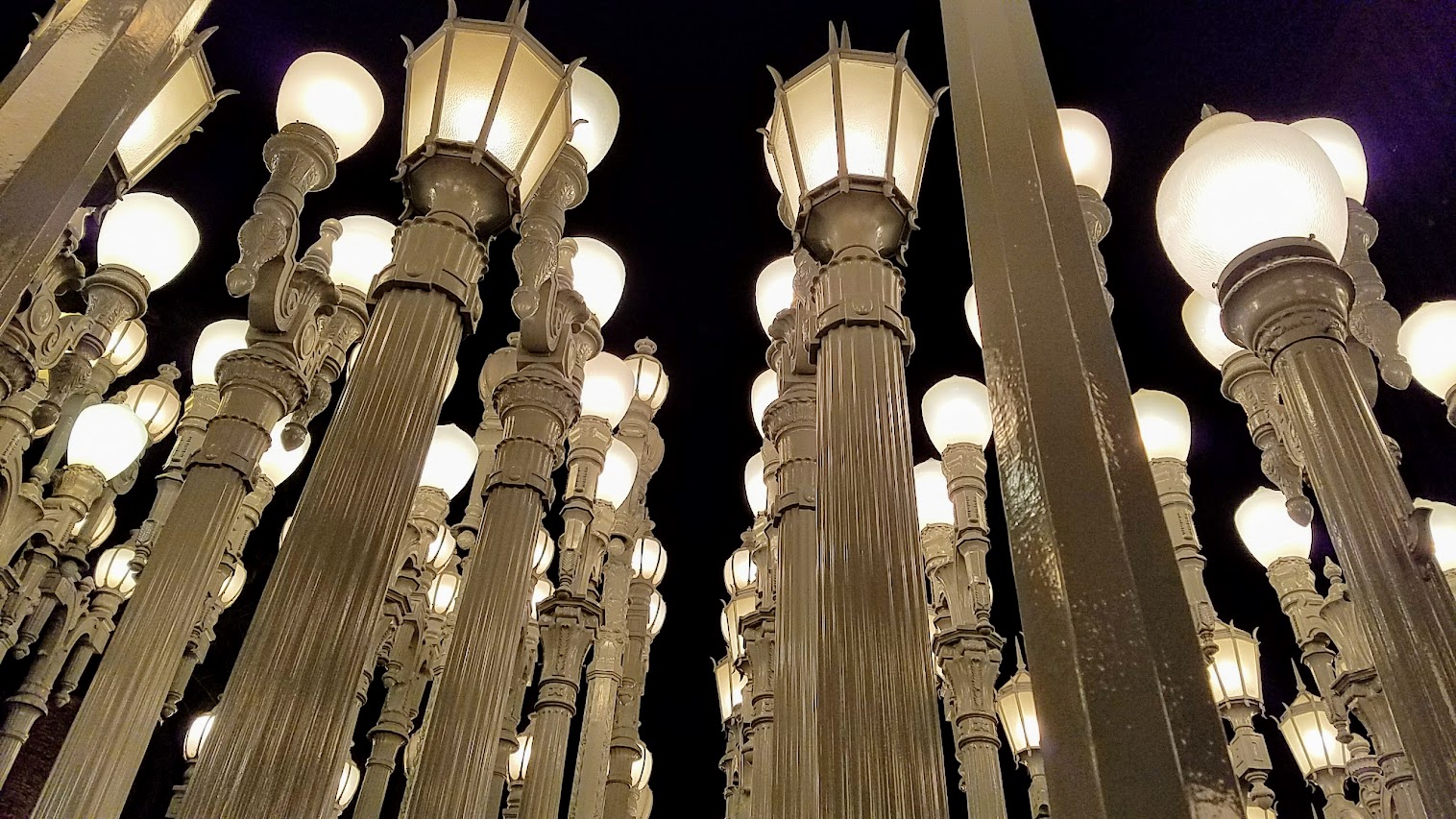 One of the most famous and free (since it is an outdoor sculpture) art you can see in the park at LACMA is the iconic Urban Lights. Created by Chris Burden, it is made of 202 restored street lamps in various styles based on where they were from (most are from southern California and some from Portland Oregon too!). The lamps are painted grey and assembled in a grid, and are solar powered and become lit in the evening. This is from an evening visit to LACMA they are open later on weekends