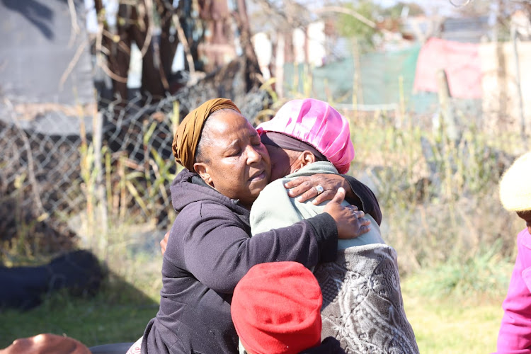 Elizabeth Phahla mother of the woman whose body was consumed by the fire, she’s being comforted by other family members.
