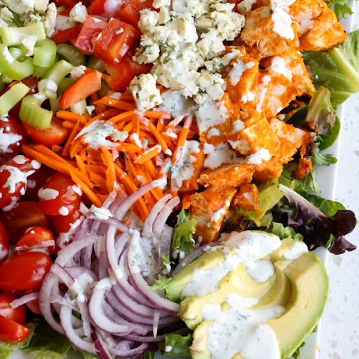 This Buffalo Chicken Salad Recipe combines buffalo chicken with sun-ripened tomatoes, shredded carrots, sweet red bell peppers, crisp celery, creamy avocado, and blue cheese crumbles all drizzled with a homemade ranch dressing.