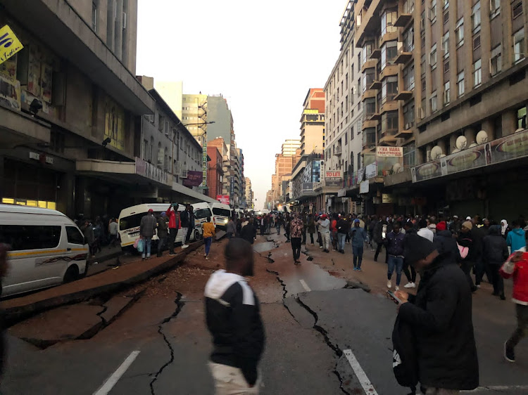 Pedestrians walk around the wreckage of an explosion on Bree Street in Joburg. Picture: BATHANDWA MALINGO