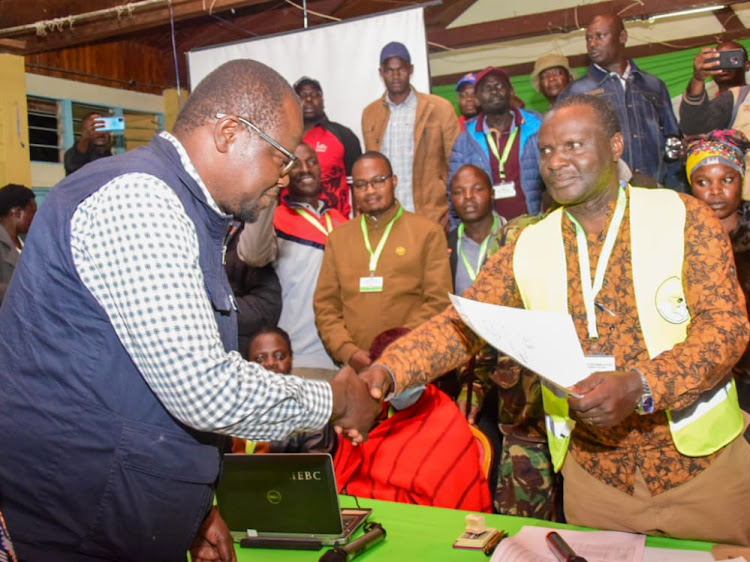 Migori Governor Ochillo Ayacko shakes hands with county IEBC returning officer Ben Moseti after being elected