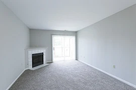 Living area with a white tile fireplace in the corner to the left and a sliding glass door to the right of the fireplace