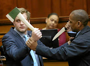 Axe-murder accused Henri van Breda, left, re-enacts in court a struggle he says took place on the night of the killing. A court official plays the part of an intruder.