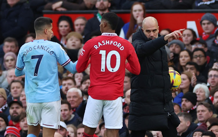 Manchester City's Joao Cancelo and Manchester United's Marcus Rashford react as City manager Pep Guardiola looks on in the Premier League match at Old Trafford in Manchester on January 14 2023.