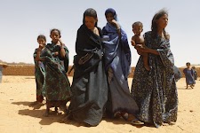 Mali.  Groep vrouwen met kleine kinderen en meisjes op zandgrond.