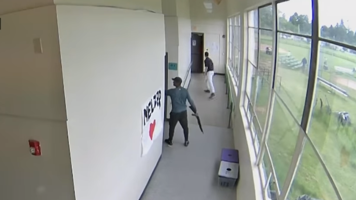 Angel Granados-Diaz is seen holding a shotgun in a school corridor.