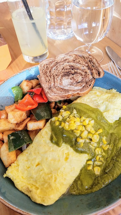 Alto Bajo Omelette a la Poblano includes three egg omelette, cheese, corn, huitlacoche, local mushrooms, poblano cream sauce, breakfast potatoes, and choice of wheat or rye toast or English muffin