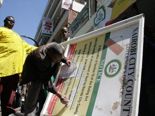 A City Council worker prepares to put up a notice on a building on Luthuli Avenue for defaulting on land rates/ COLLINS KWEYU