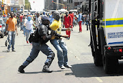 FACELESS CRUSADER: Tshwane University of Technology students rampage through the streets of the Pretoria CBD yesterday, but were tackled by police, who fired rubber bullets and stun grenades