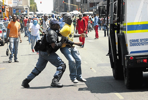 FACELESS CRUSADER: Tshwane University of Technology students rampage through the streets of the Pretoria CBD yesterday, but were tackled by police, who fired rubber bullets and stun grenades