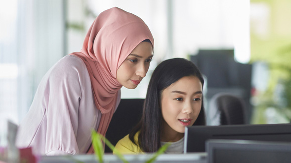 Dua perempuan sedang melihat laptop