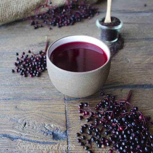 Cup of elderberry tea with fresh elderberries on the table 