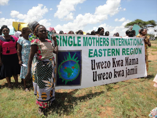 Single mothers and widowed women who turned up for the official launch of the Easter Region Chapter of the Single Mothers International (SMI) at Nguutani Mwingi West display a banner./FILE