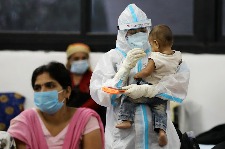 A medical worker in personal protective equipment (PPE) plays with a child of woman recovering inside a quarantine centre for Covid-19 patients at an indoor sports complex in New Delhi, India.