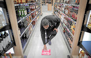 A staffer at Tops at Spar in Blackheath places social distancing stickers on the floor on  May 20  preparing for the sale of alcohol on  June 1. The ban was  later reinstated.   /Sebabatso Mosamo/Sunday Times