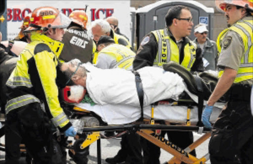 BLOODY AFTERMATH: A runner is escorted from the scene after explosions went off at the 117th Boston Marathon in Boston, Massachusetts, yesterday. Two explosions hit the marathon as runners crossed the finish line, killing at least two people and injuring 23 on a day when tens of thousands of people pack the streets to watch one of the world's best-known marathons. PHOTOS: REUTERS and getty IMAGES