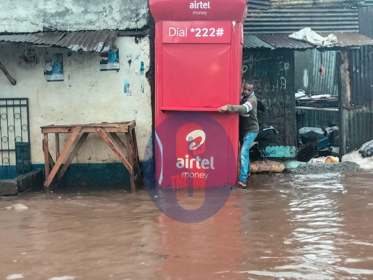 A man supports himself as he tries to find a place to step on following downpour in Nairobi on November 14,2022