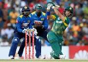 South Africa's JP Duminy (R) hits a boundary next to Sri Lanka's wicketkeeper Niroshan Dickwella (L) and captain Angelo Mathews (C) during the first ODI match in Dambulla on July 29, 2018.