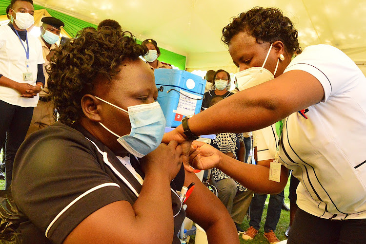 Kakamega County General Hospital head of nursing officers Jacinta Angote receives a Covid-19 jab from nursing officer Beverlyne Wambani on Friday