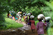 Flood victims from Mtauchira village carry food they received from the Malawi government in the aftermath of Cyclone Freddy that destroyed their homes. 